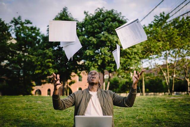 professional headshot of a black man throwing books in the sky